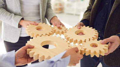 Três pessoas a segurar engrenagens de madeira